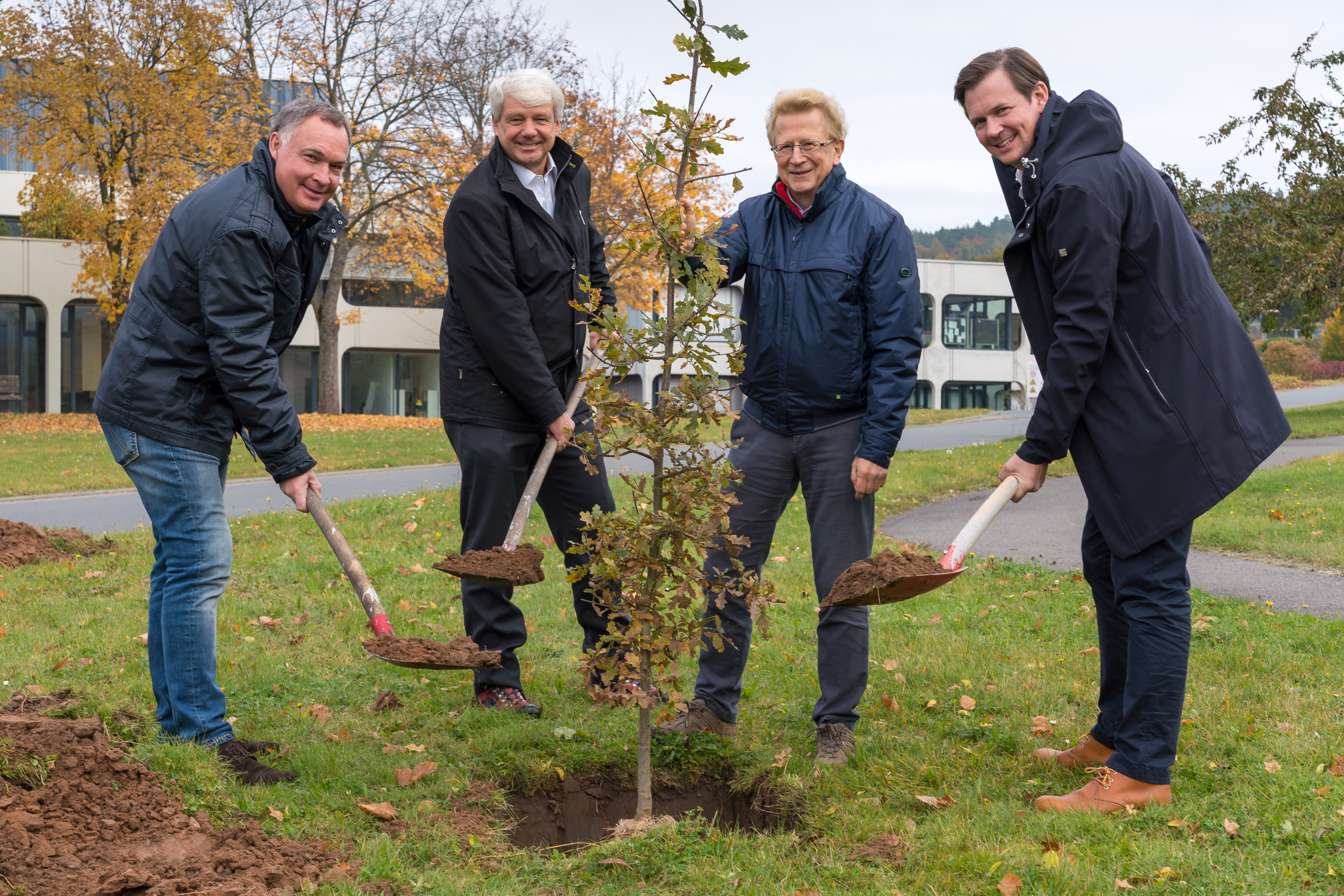 Michael Stiehl, Jochen Arndt, Andreas Gerecke und Dirk Streiber pflanzen vor dem Hauptfirmensitzes in Freudenberg vier junge Bäume.