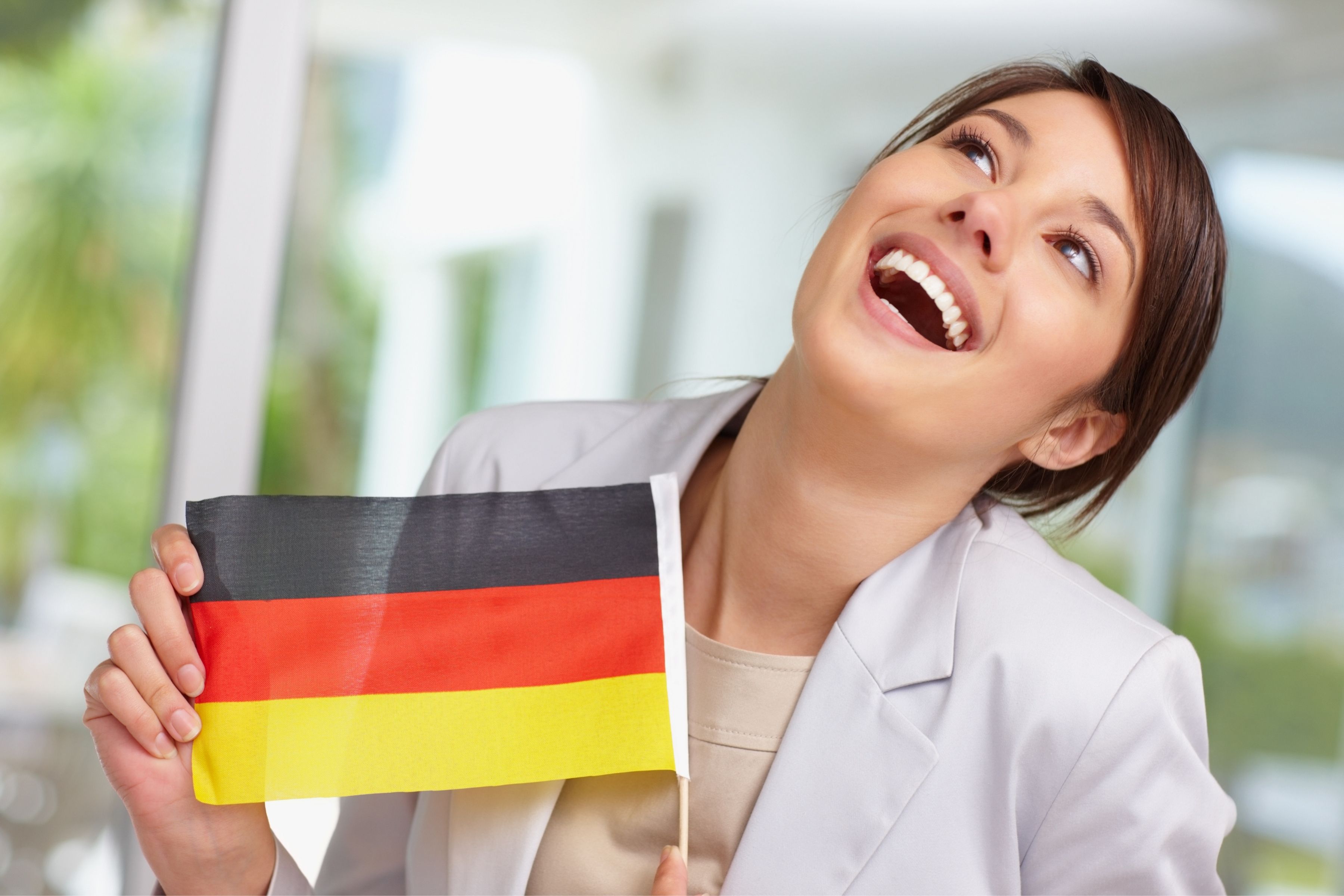 Lachende Dame hält Deutschland-Flagge in der Hand.